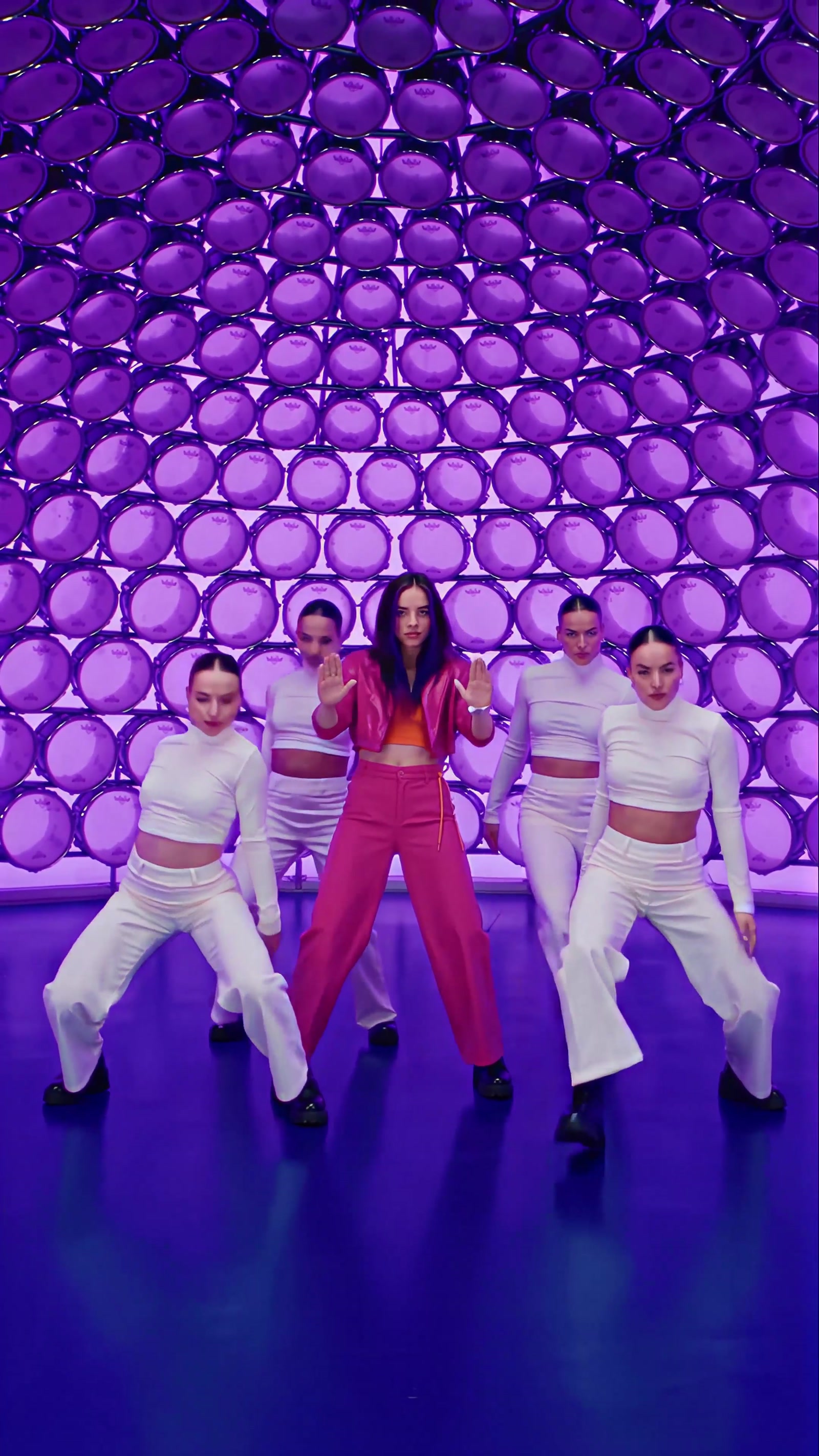 Four dancers in identical white in a wide stance, the soloist upright between them