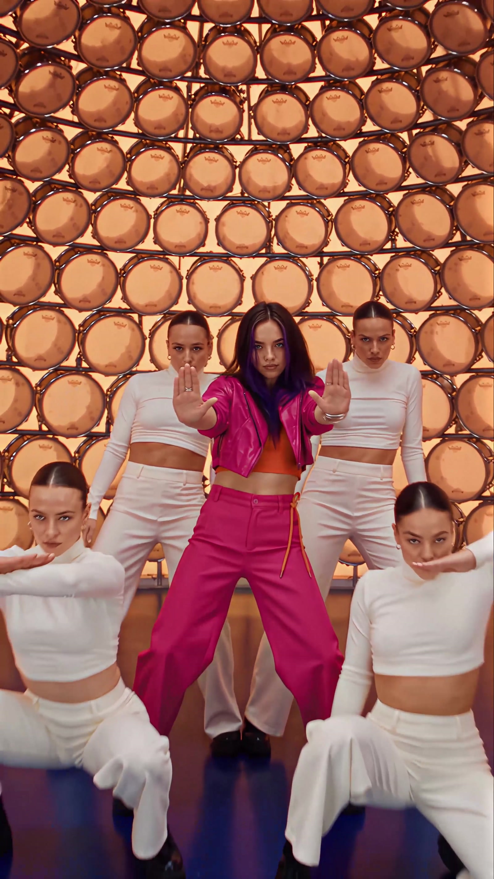 Frame from the video: the same face and wardrobe against the drum wall